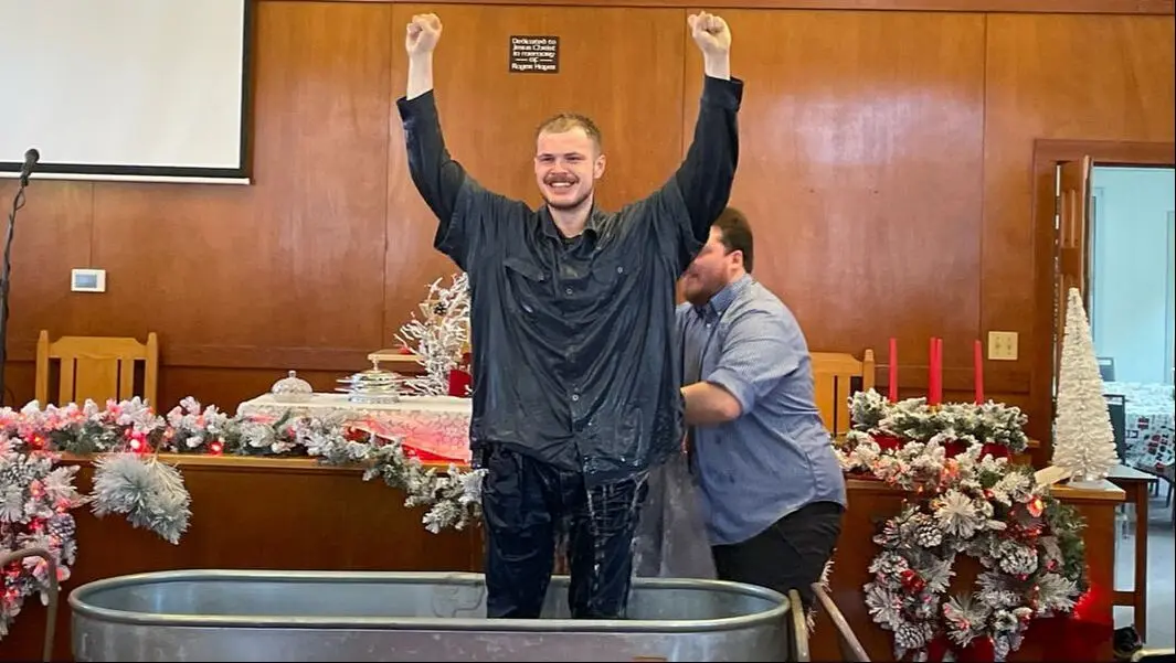 A new believer celebrates after being baptized in the church sanctuary