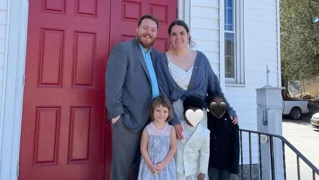Pastor Taylor Callen with his wife Caiti and their children outside the red church doors